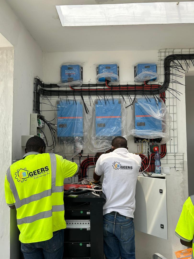 Techniciens GEERS raccordant une banque d'onduleurs Victron sur un chantier à Kinshasa