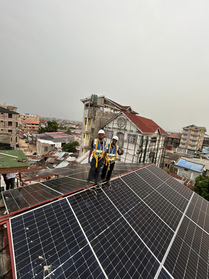 Techniciens GEERS harnachés posant des panneaux solaires sur une toiture à Kinshasa